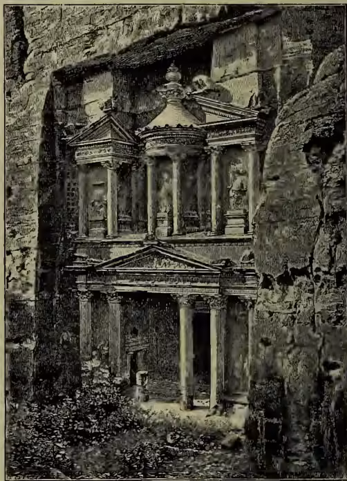 A black and white engraving of the Rock Temple at Petra, known as El Khusna. The image shows a multi-story structure built into a massive, light-colored rock face. The building features classical architectural elements, including columns, pediments, and niches. The structure is partially ruined, with some sections missing, revealing the interior. The rock face is rugged and textured, with some vegetation visible at the base of the structure.