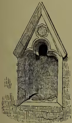 A detailed black and white line drawing of a piscina, which is a small, arched stone basin. It has a decorative triangular pediment above the opening and a small drain pipe at the bottom. The drawing is labeled 'Piscina' below it.