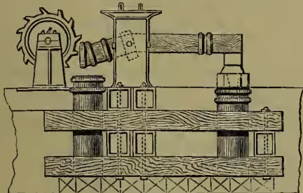 A technical diagram of a tilt hammer mechanism. It shows a horizontal rotating wheel with several cam-like projections. A vertical rod is attached to the wheel, and a heavy, rectangular faggot is suspended from the rod. The faggot is shown in a tilted position, indicating the action of the cam. The entire mechanism is mounted on a base with a cross-hatched pattern.